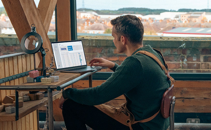 Photo of man sitting at desk looking at his laptop