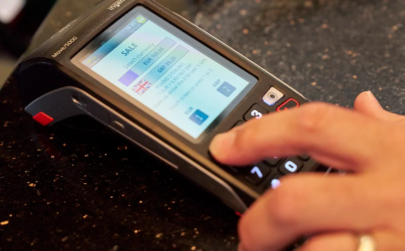 Payment terminal on table with customer deciding what currency to pay in