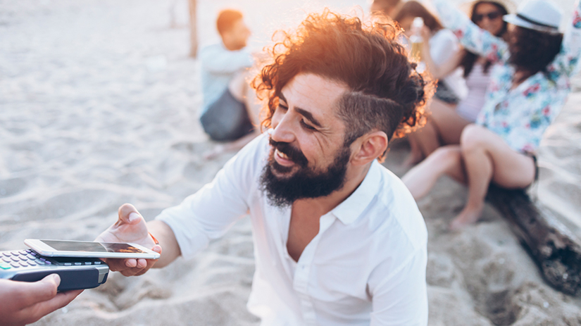 man paying with a smartphone on the beach