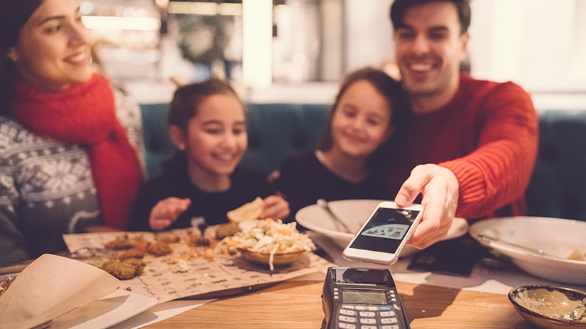 family in restaurant paying contactless